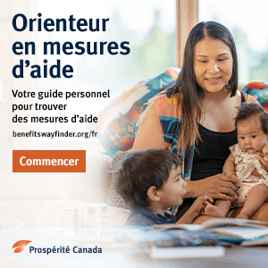 Une mère autochtone, sourire aux lèvres et un bébé dans les bras, est assise avec un jeune enfant sur un divan devant des livres posés sur une table.